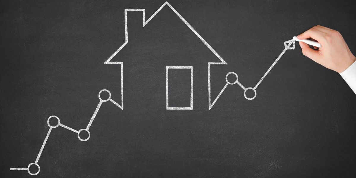 Hand drawing a rising line chart over a chalk outline of a house, representing mortgage rate growth.