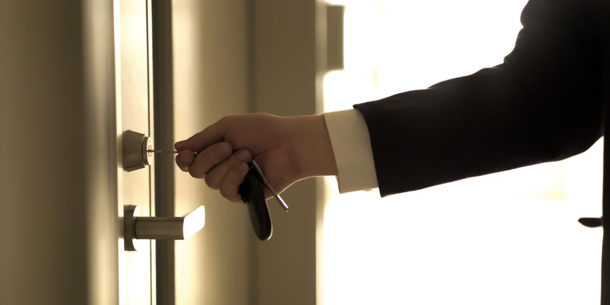 Person in a suit unlocking a door with a key